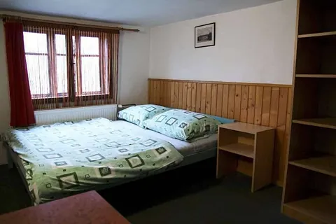 Pokoj s manželskou postelí, nočním stolkem a regálem